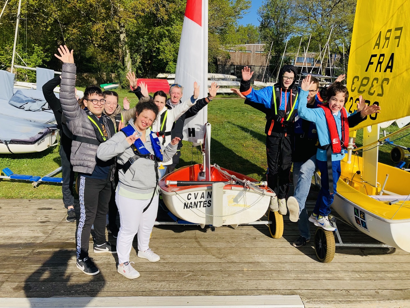 Les jeunes handicapés, accompagnés de leurs éducateurs et du moniteur, lèvent les bras au ciel pour une photo souvenir sur le ponton du club de voile