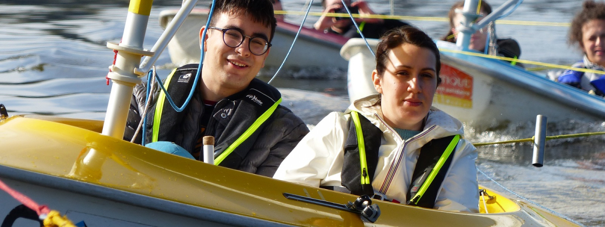 Un jeune handicapé navigue à bord d'un dériveur adapté aux côtés de son éducatrice spécialisée