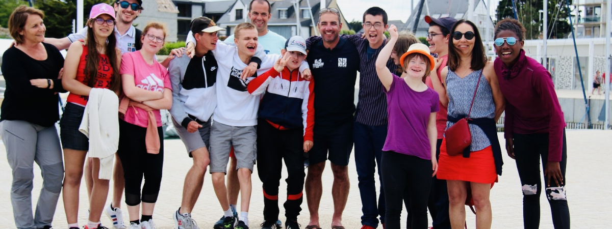 Le skippeur Damien Seguin entouré d'un groupe de jeunes handi bras dessus bras dessous