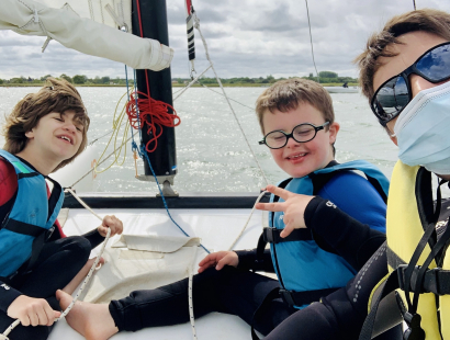 Deux jeunes handicapés tout sourire à bord d'un catamaran avec leur éducatrice spécialisée.